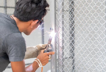 Worker is welding a steel net on door.