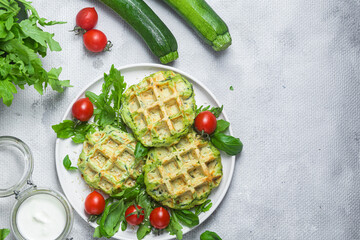 Zucchini waffles with arugula and cherry tomatoes in a plate