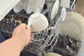 woman puts a white mug in the dishwasher