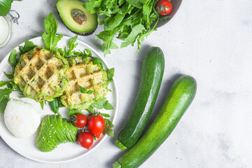 Zucchini waffles, poached egg, avocado and cherry tomatoes in a plate