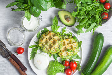 Zucchini waffles, poached egg, avocado and cherry tomatoes in a plate