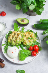 Zucchini waffles, poached egg, avocado and cherry tomatoes in a plate