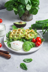 Zucchini waffles, poached egg, avocado and cherry tomatoes in a plate