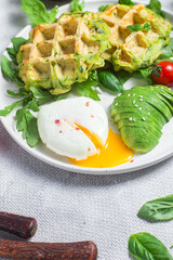 Zucchini waffles, poached egg, avocado and cherry tomatoes in a plate