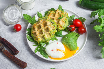 Zucchini waffles, poached egg, avocado and cherry tomatoes in a plate