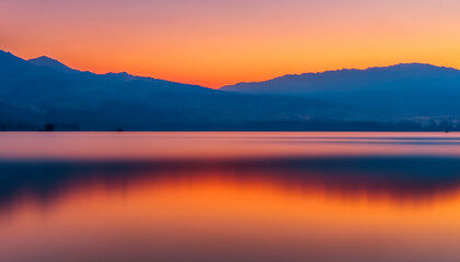 Fototapeta na wymiar sunrise over the lake with mountain and orange sky