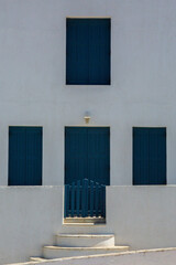 Old traditional style white house with blue wooden door and windows in Mykonos, Cyclades, Greece.