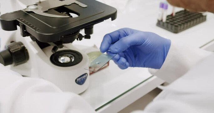 Male doctor using microscope in laboratory.Examining blood under the high-tech microscope equipment.Man in lab coat and latex gloves using microscope to examine sample during work in clinic in daytime