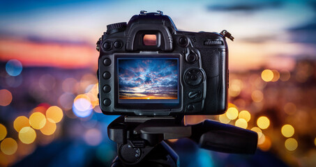 Camera on the background of city lights and sunset. Concept on the topic of photography and photo...