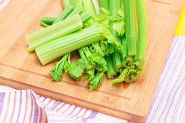 Fresh Celery Stem and Chopped Celery Sticks on Wooden Cutting Board. Vegan and Vegetarian Culture. Raw Food. Healthy Diet with Negative Calorie Content. Slimming Food
