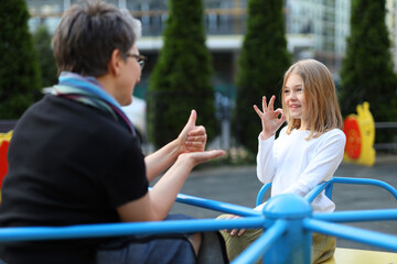 A deaf girl speaks sign language With a teacher on the playground. © Andrii Zastrozhnov