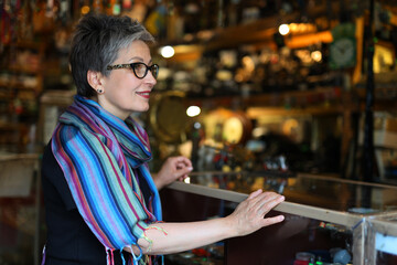 Mature woman looking at different vintage items in an old flea market shop.