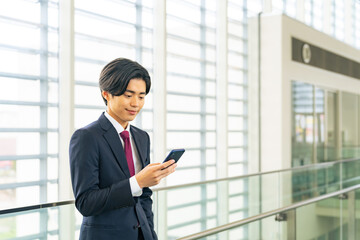 Fototapeta premium ロビーでスマホを使う若いビジネスマン