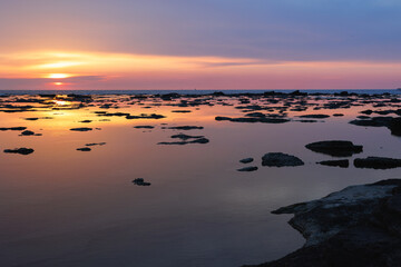 Sunset Reflected on the Sea as in a Mirror with Rocks Emerging on the Surface of the Water