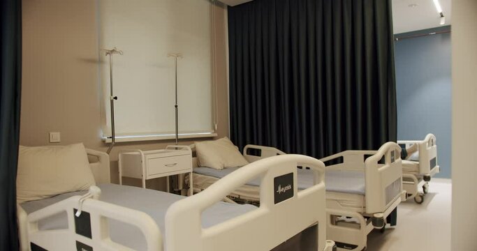 Two empty bed in a hospital room with medical equipment. View beds in hospital ward with white clean bedding. Cozy room in medical clinic indoors with no people. Concept of medicine and service.