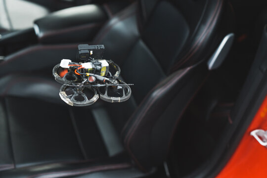 Modern technology. Small FPV drone flying over black leather car seat. Blurred background. Car detailing process filmed by a drone. High quality photo