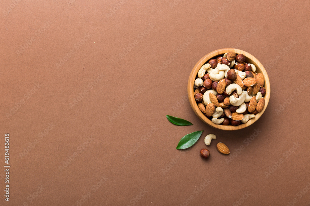 Wall mural Assortment of nuts in wooden bowl on colored table. Cashew, hazelnuts, walnuts, almonds. Mix of nuts Top view with copy space - Wall murals