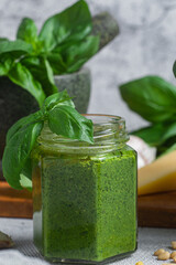 Pesto sauce in a glass jar on the table. Basil