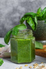 Pesto sauce in a glass jar on the table. Basil