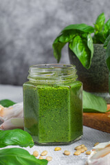Pesto sauce in a glass jar on the table. Basil