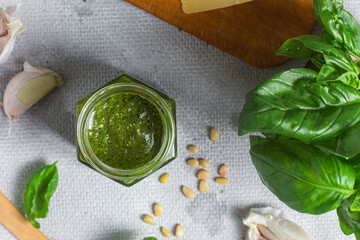Pesto sauce in a glass jar on the table. Basil