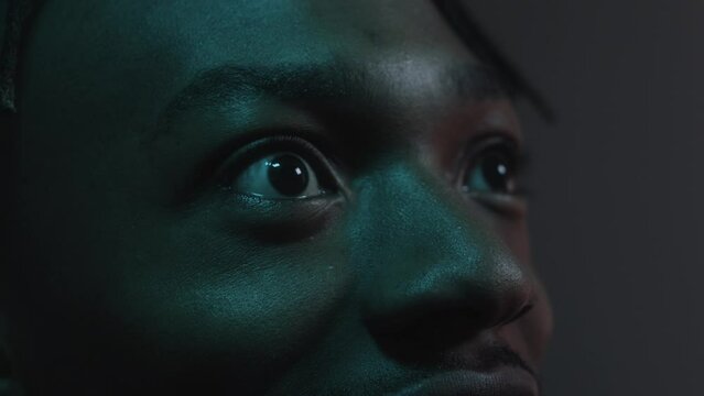 Man reacting with amazement to something on the big screen while his face lights up with colours