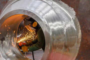 A worker processes nozzle of the reactor vessel with special equipment.