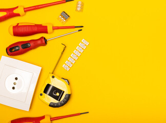 Electrician equipment on yellow background with copy space.Top view.Electrician tool set.Multimeter, tester,screwdrivers,cutters,duct tape,lamps,tape measure and wires.Flet lay. © Avocado_studio