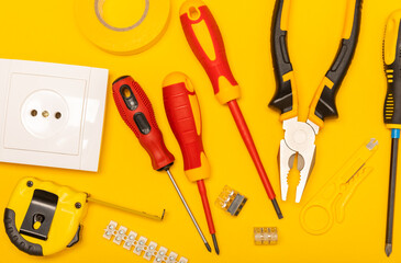 Electrician equipment on yellow background with copy space.Top view.Electrician tool set.Multimeter, tester,screwdrivers,cutters,duct tape,lamps,tape measure and wires.Flet lay. © Avocado_studio