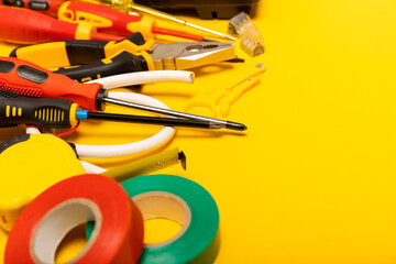 Electrician equipment on yellow background with copy space.Top view.Electrician tool set.Multimeter, tester,screwdrivers,cutters,duct tape,lamps,tape measure and wires.Flet lay. © Avocado_studio