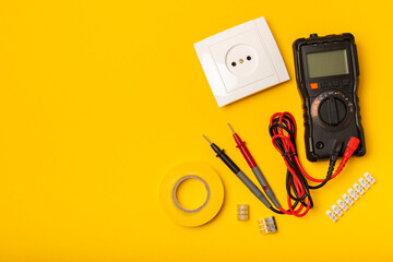 Electrician equipment on yellow background with copy space.Top view.Electrician tool set.Multimeter, tester,screwdrivers,cutters,duct tape,lamps,tape measure and wires.Flet lay. © Avocado_studio