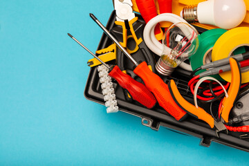 Electrician equipment on blue background with copy space.Top view.Electrician tool set.Multimeter, tester,screwdrivers,cutters,duct tape,lamps,tape measure and wires.Flet lay. © Avocado_studio