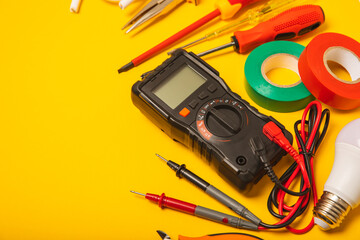 Electrician equipment on yellow background with copy space.Top view.Electrician tool set.Multimeter, tester,screwdrivers,cutters,duct tape,lamps,tape measure and wires.Flet lay. © Avocado_studio