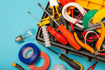 Electrician equipment on blue background with copy space.Top view.Electrician tool set.Multimeter, tester,screwdrivers,cutters,duct tape,lamps,tape measure and wires.Flet lay. © Avocado_studio