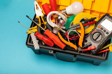 Electrician equipment on blue background with copy space.Top view.Electrician tool set.Multimeter, tester,screwdrivers,cutters,duct tape,lamps,tape measure and wires.Flet lay. © Avocado_studio