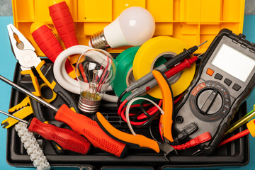 Electrician equipment on blue background with copy space.Top view.Electrician tool set.Multimeter, tester,screwdrivers,cutters,duct tape,lamps,tape measure and wires.Flet lay. © Avocado_studio