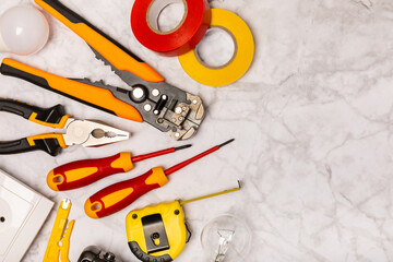 Electrician equipment on marble background with copy space.Top view.Electrician tool set.Multimeter, tester,screwdrivers,cutters,duct tape,lamps,tape measure and wires.Flet lay.