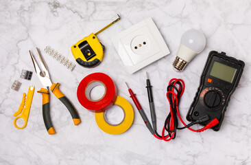 Electrician equipment on marble background with copy space.Top view.Electrician tool set.Multimeter, tester,screwdrivers,cutters,duct tape,lamps,tape measure and wires.Flet lay. © Avocado_studio