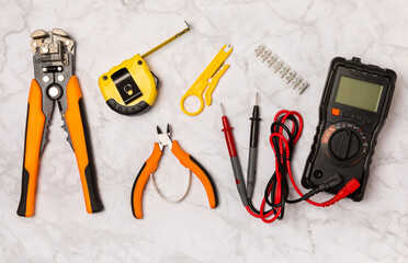 Electrician equipment on marble background with copy space.Top view.Electrician tool set.Multimeter, tester,screwdrivers,cutters,duct tape,lamps,tape measure and wires.Flet lay. © Avocado_studio