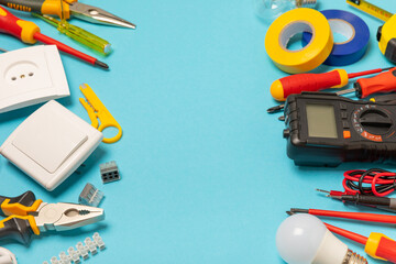 Electrician equipment on blue background with copy space.Top view.Electrician tool set.Multimeter, tester,screwdrivers,cutters,duct tape,lamps,tape measure and wires.Flet lay. © Avocado_studio