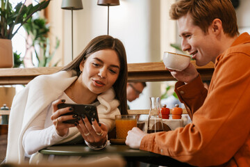 Couple using mobile phone while sitting in cafe