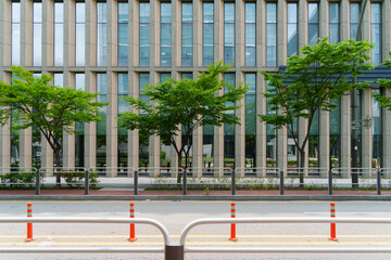 Road side view in front of a building with glass windows. A blocking fence is installed between the...