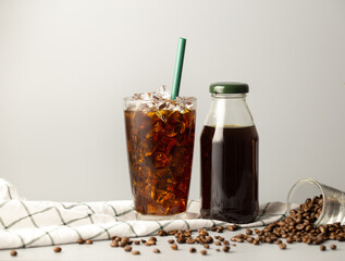 Iced americano coffee with coffee beans on grey background, Black coffee glass package for takeaway. Cold beverage product.