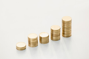 Stack of coins on white table. Graph or chart for investing in stock market. Gold management for wealth.