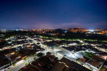 Fototapeta premium Dramatic night sky image of the city of Pedreira, in the interior of São Paulo. Mix of orange and purple colors with stars. Long exposure.