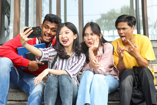 Multicultural college students having fun taking selfie picture with funny face expression using smartphone 