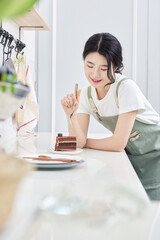 Obraz na płótnie Canvas young Asian female model who makes a piece of cake in the kitchen and eats it deliciously