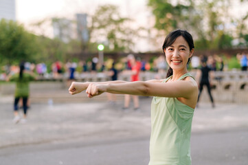 Female jogger. Fit young Asian woman with green sportswear aerobics dance exercise in park and enjoying a healthy outdoor. Fitness runner girl in public park. Wellness being concept