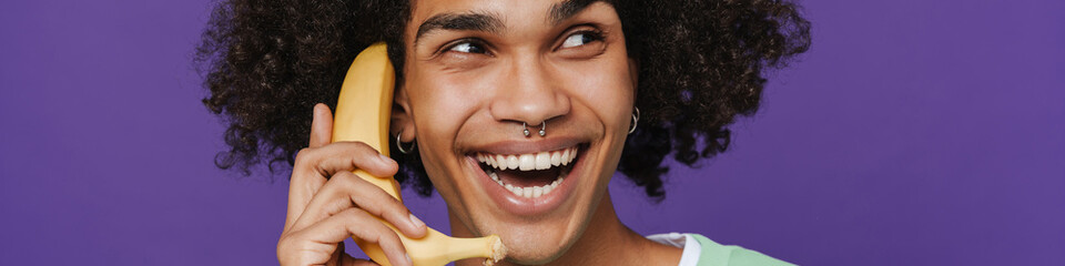 Young smiling happy latin man talking on banana like phone