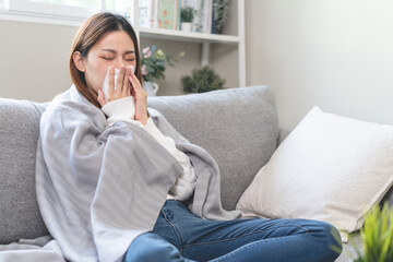 Seasonal sick concept. the young woman has a common cold and sneezing on the sofa.